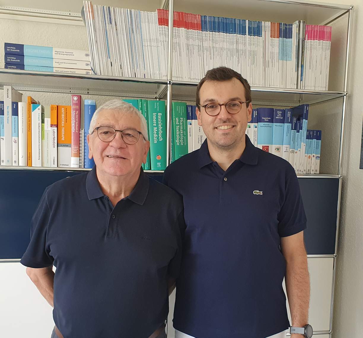 Dr. Burger und Kollege vor einem Bücherregal